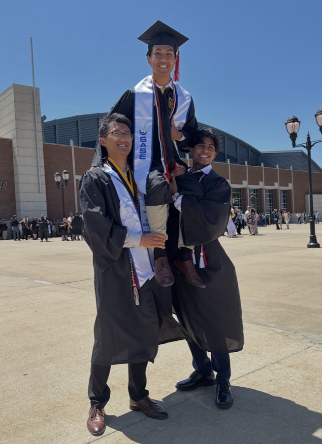 Eric in cap and gown being hoisted up by his two roommates at Mizzou graduation
